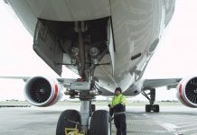 Inspector examining nosewheel of jet aircraft