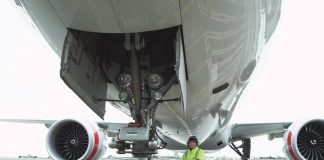 Inspector examining nosewheel of jet aircraft