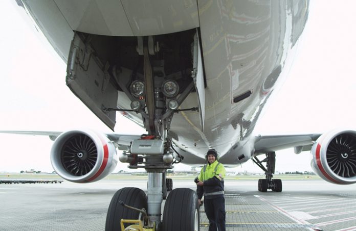 Inspector examining nosewheel of jet aircraft