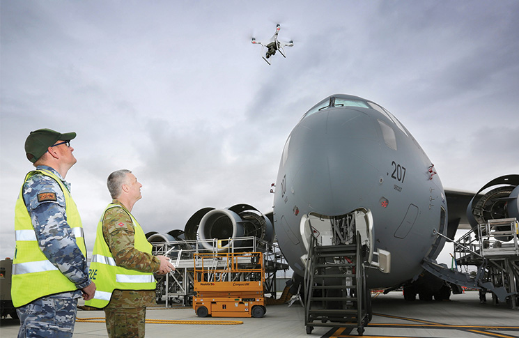 Australian Army soldier, Sergeant Andrew Whitelaw, from 16 Air Land Regiment and Corporal Kelvin Green, Aircraft Surface Finisher at Royal Australian Air Force No.36 Squadron, launch a Phantom 4 to inspect the condition of paint on the upper surfaces of a C-17A Globemaster on the flightline at RAAF Base Amberley