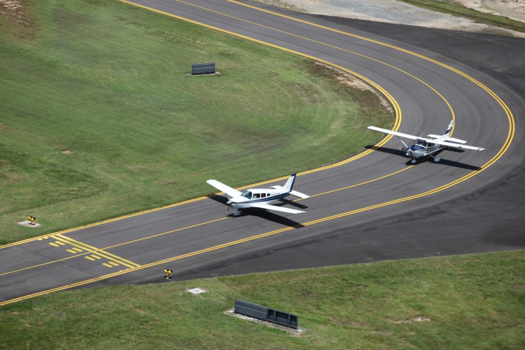 Aerial view of a Piper and Cessna lined up on the taxiway at Cairns Airport.