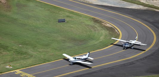 Aerial view of a Piper and Cessna lined up on the taxiway at Cairns Airport.