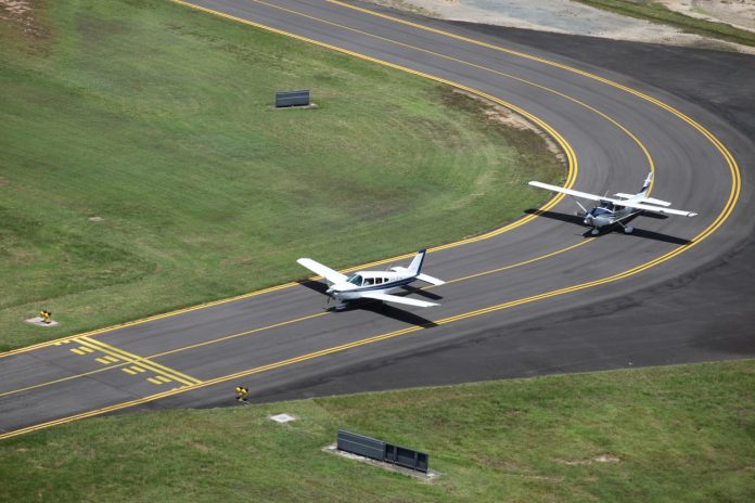 Aerial view of a Piper and Cessna lined up on the taxiway at Cairns Airport.