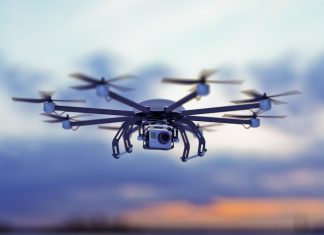 Octocopter drone flying against a dusk sky.