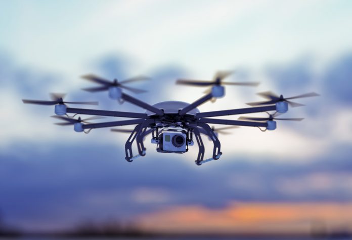 Octocopter drone flying against a dusk sky.