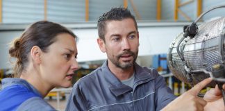 Two maintenance engineers in aircraft hangar examining dismantled part