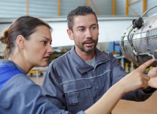 Two maintenance engineers in aircraft hangar examining dismantled part