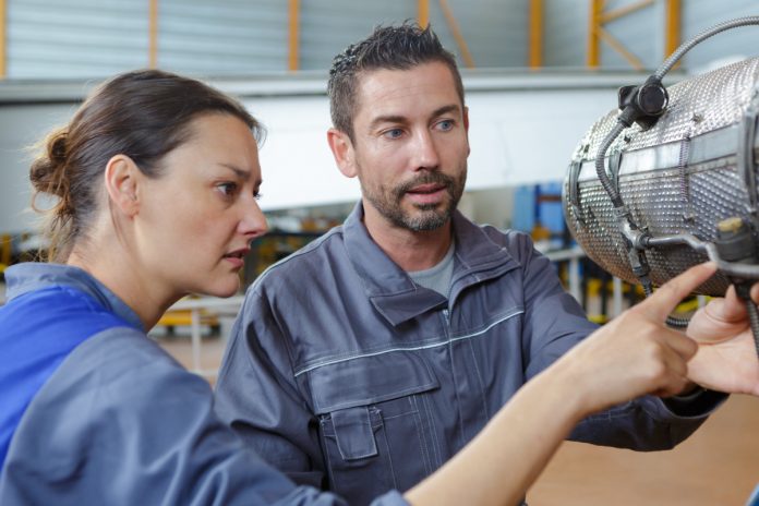 Two maintenance engineers in aircraft hangar examining dismantled part