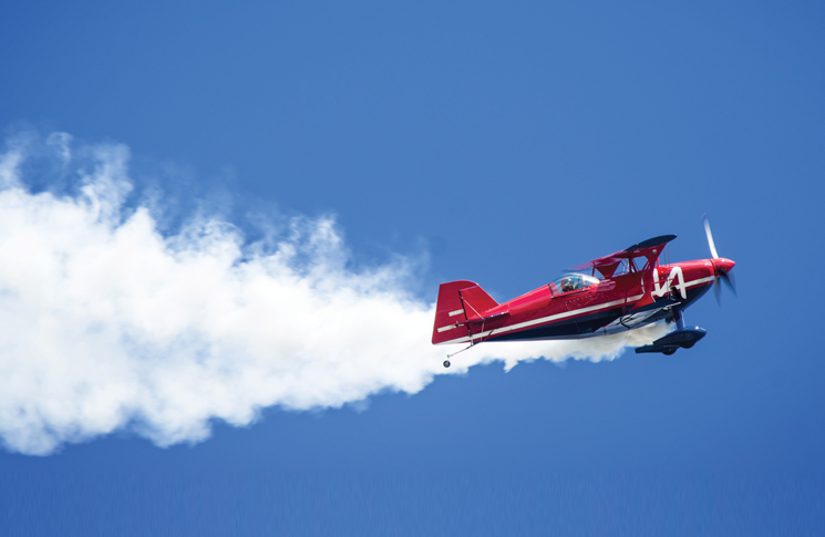 Airshow plane leaving a smoke trail on a blue sky background