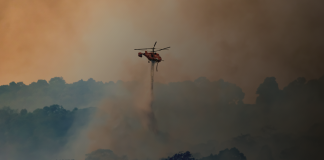 Helicopter water bomber putting out fires in a bushland environment