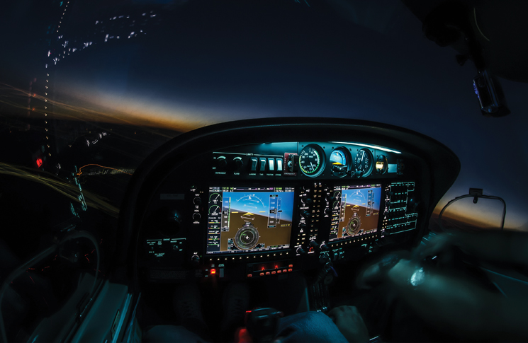 Lightened up cockpit and avionics in aircraft flying at night with beautiful twilight in background