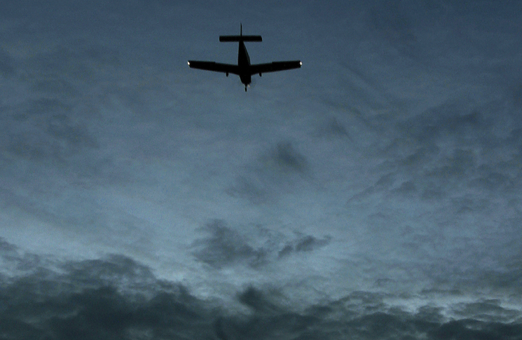 Silhouette of small aircraft in the sky at dusk