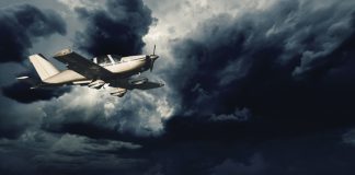 Small aircraft flying in storm clouds with lightning