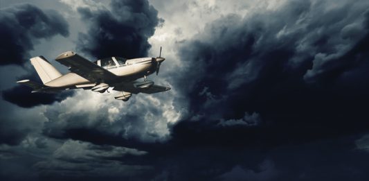 Small aircraft flying in storm clouds with lightning