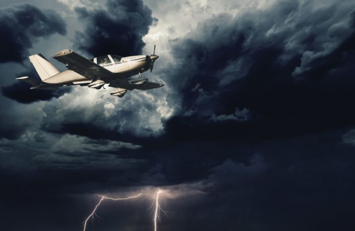 Small aircraft flying in storm clouds with lightning