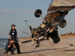 Two police officer investigating a gyrocopter crash on a beach.