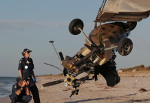 Two police officer investigating a gyrocopter crash on a beach.