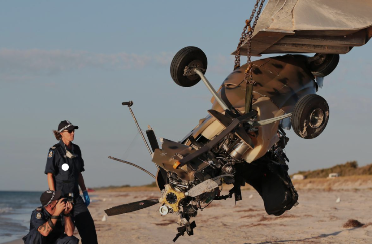 Two police officer investigating a gyrocopter crash on a beach.