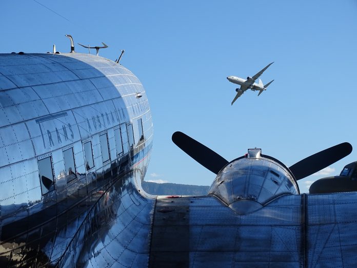Photo by Ian Leithhead. Parked Trans Australia Airlines Douglas DC-3 and Boeing P-8 Poseidon in flight overhead.