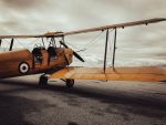 Photo by Tomasz Sobkow. Parked yellow DH-82A Tiger Moth biplane.