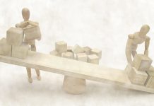 abstract wooden puppets figures balancing cube shapes on a set of wooden scales