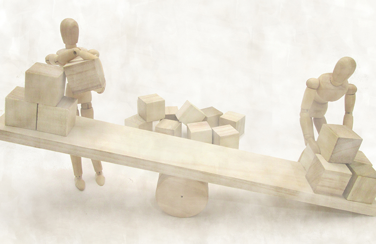 abstract wooden puppets figures balancing cube shapes on a set of wooden scales