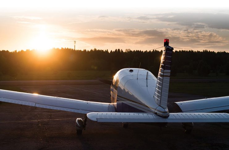 Aircraft parked at an airfield. Rear view of a plane with a propeller on a sunset background.