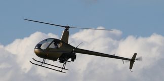 Robinson R22 helicopter flying with clouds in the background