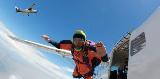 Skydiver jumping out of a plane with a second small aircraft in the background