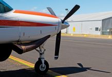 Photo of the front of a small aircraft with a propellor on the tarmac
