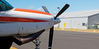 Photo of the front of a small aircraft with a propellor on the tarmac