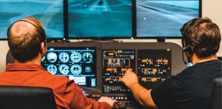 Photo of two males operating a home flight simulator