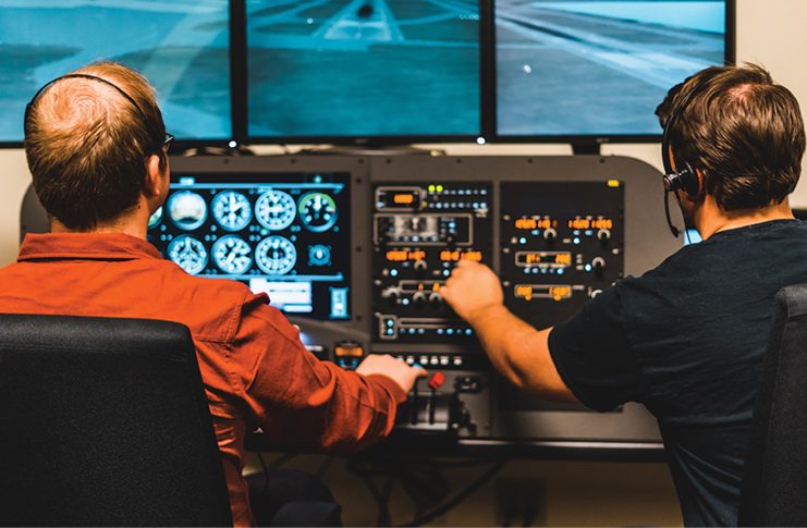 Photo of two males operating a home flight simulator