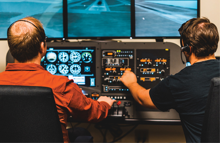 Photo of two males operating a home flight simulator
