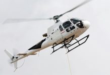 White helicopter flying in a cloudy white sky