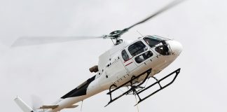 White helicopter flying in a cloudy white sky