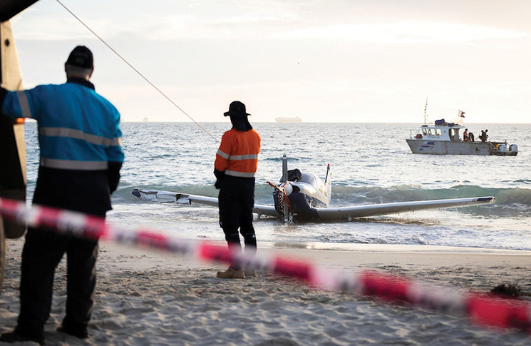 Image of a salvage crew winching the light plane out of the water