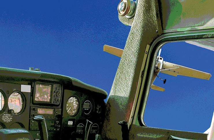 Image of a small aircraft flying dangerously close outside the cockpit window of another plane