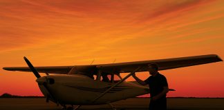 Image of pilot inspecting light aircraft at sunset