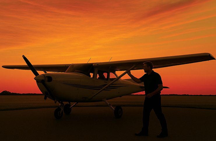 Image of pilot inspecting light aircraft at sunset