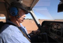 Man wearing headset flying a small aircraft over dry outback terrain. Credit: CASA