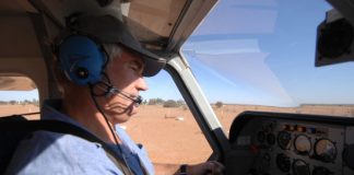 Man wearing headset flying a small aircraft over dry outback terrain. Credit: CASA