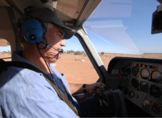 Man wearing headset flying a small aircraft over dry outback terrain. Credit: CASA