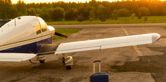 Weight and balance: your first line of defence A blue suitcase and a parked small private jet. Quadruple plane with a propeller for an air taxi in the sunset.