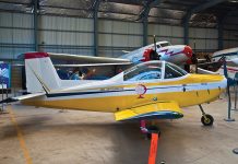 A yellow and white aeroplane is parked in a hangar.