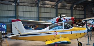 Age must not weary them A yellow and white aeroplane is parked in a hangar.
