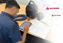 A man is sitting at a table with an electronic flight bag and a backpack.
