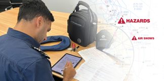 A man is sitting at a table with an electronic flight bag and a backpack.
