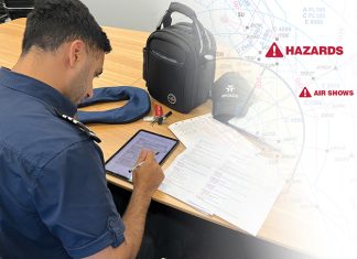 A man is sitting at a table with an electronic flight bag and a backpack.