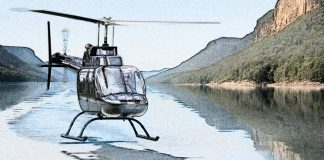 A helicopter hovering over mirror-smooth lake water